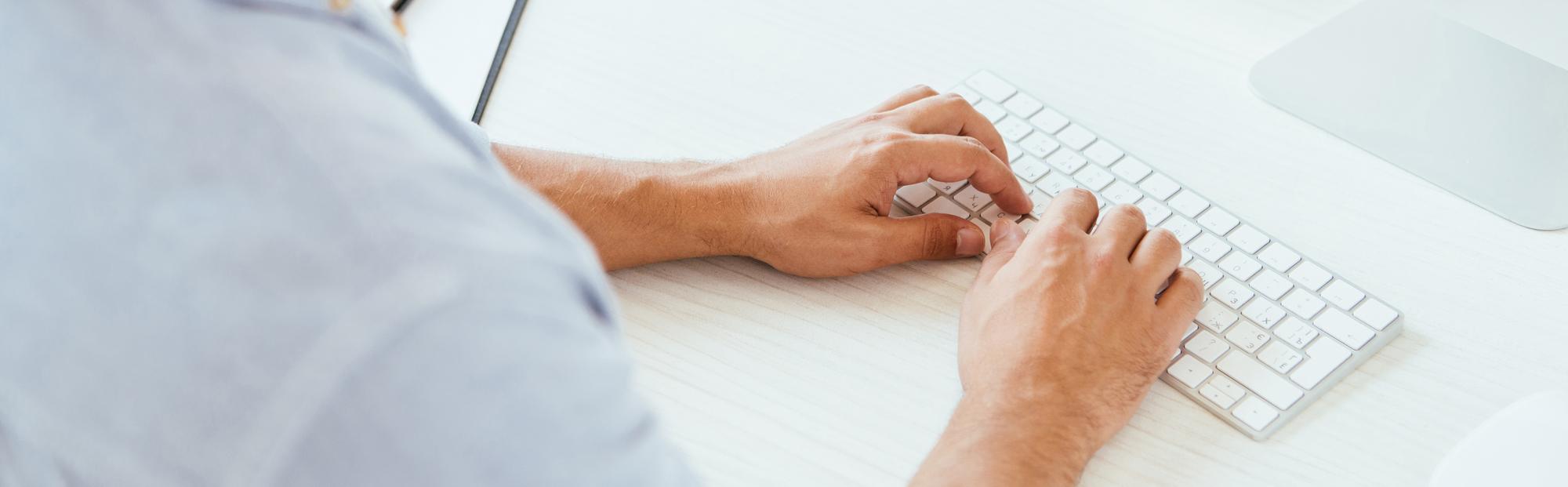 photo looking over shoulders of person with hands on a keyboard